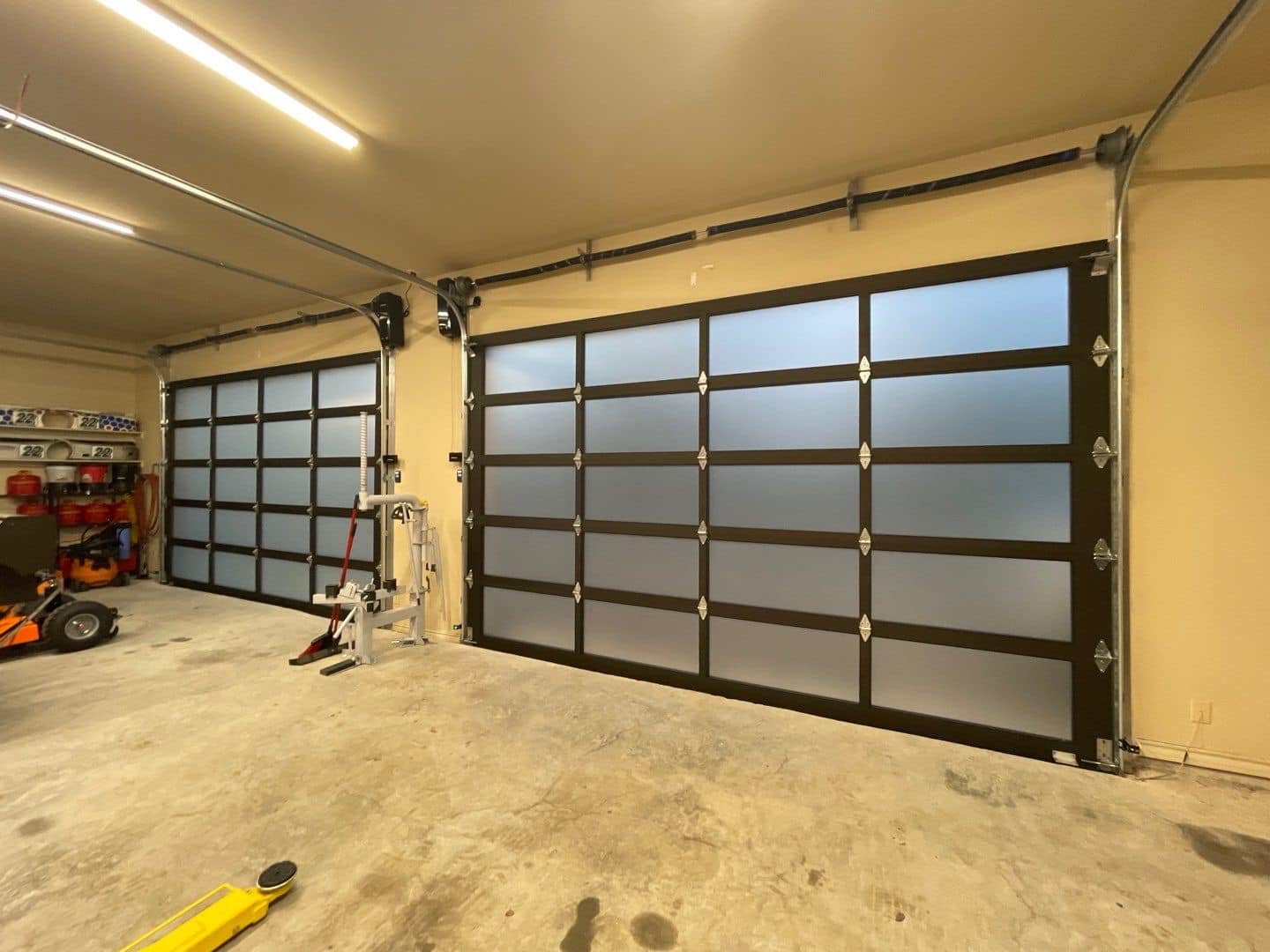 Full-view aluminum and frosted glass garage doors installed in a residential garage